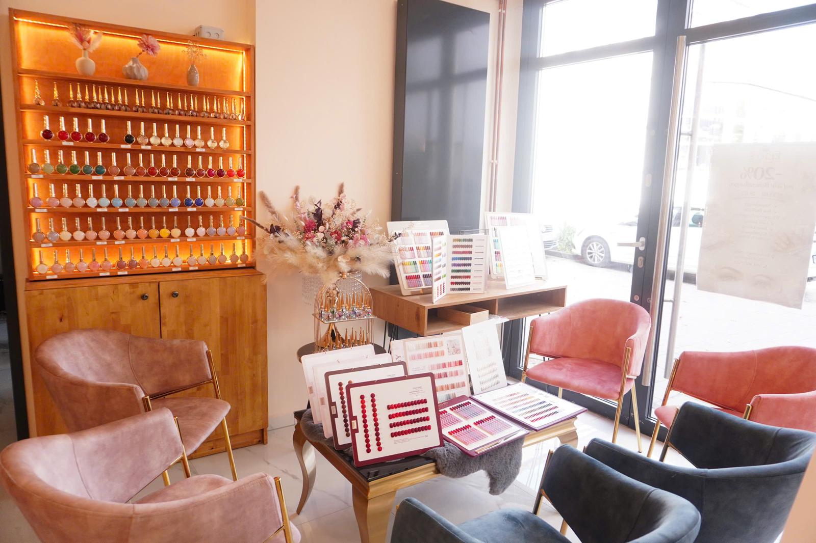 Empfangsbereich mit Gelnägel-Farbauswahl und rosa Samtsesseln im Nagelstudio Elio's Nails & Spa Hamburg